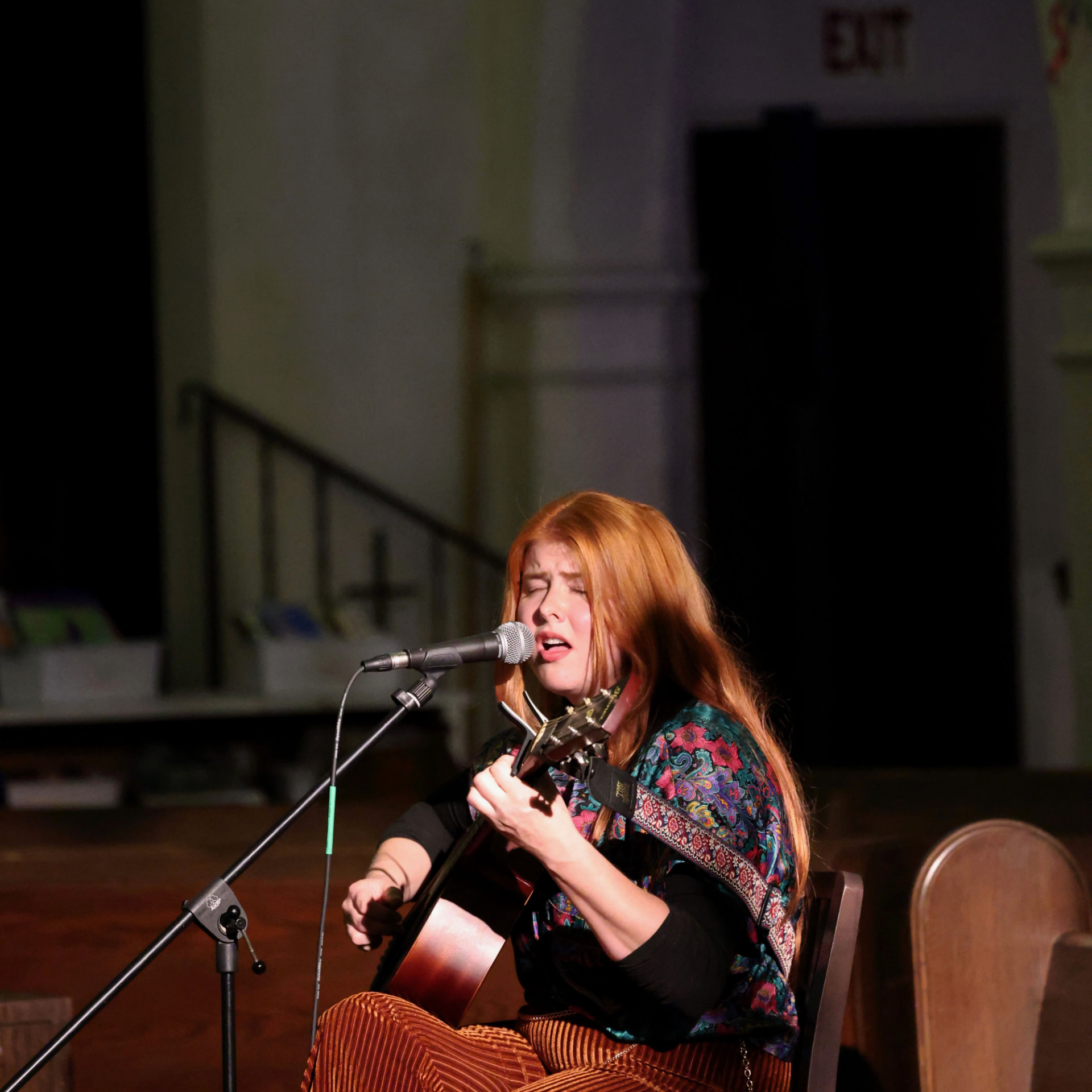 Kaylee Daugherty singing and playing acoustic guitar on stage