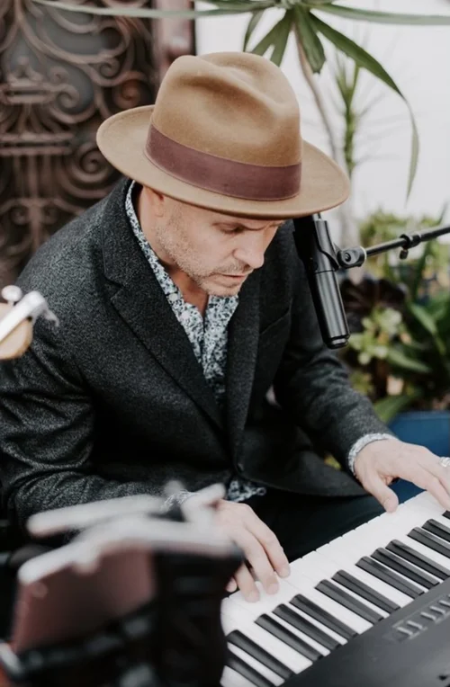 Eric performing at the keyboard in a hat and dark jacket